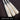 Three white handcrafted Mark Lumber Torpedo wood baseball bats in hard maple engraved with model 13‑TRPD on textured brown turf.