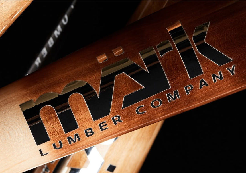 Close-up of a Mark Lumber wood baseball bat engraved with the company logo.