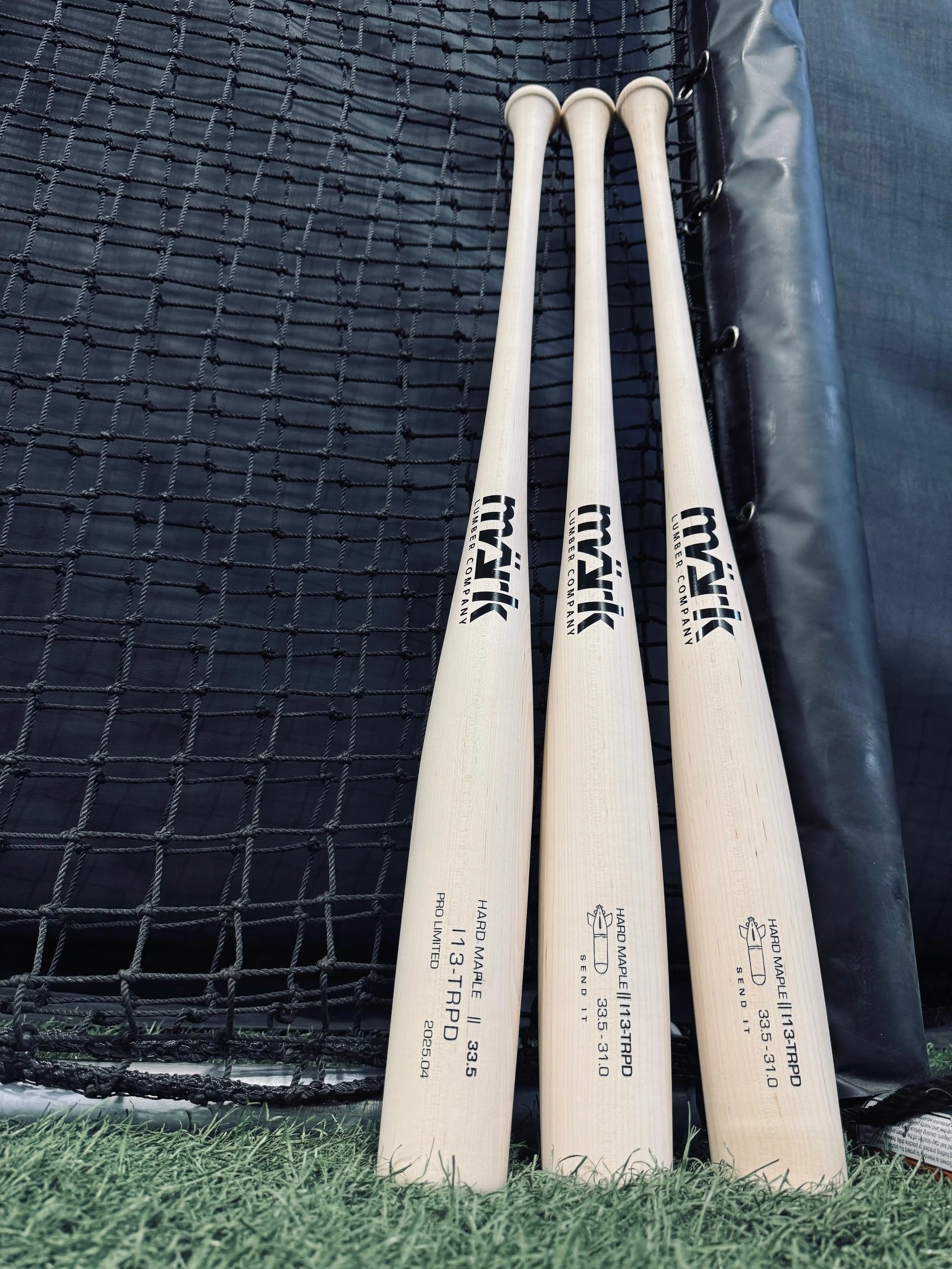 Wood baseball bats are lined up before a net, showing engraved logos and model details to compare a torpedo bat to a regular bat.