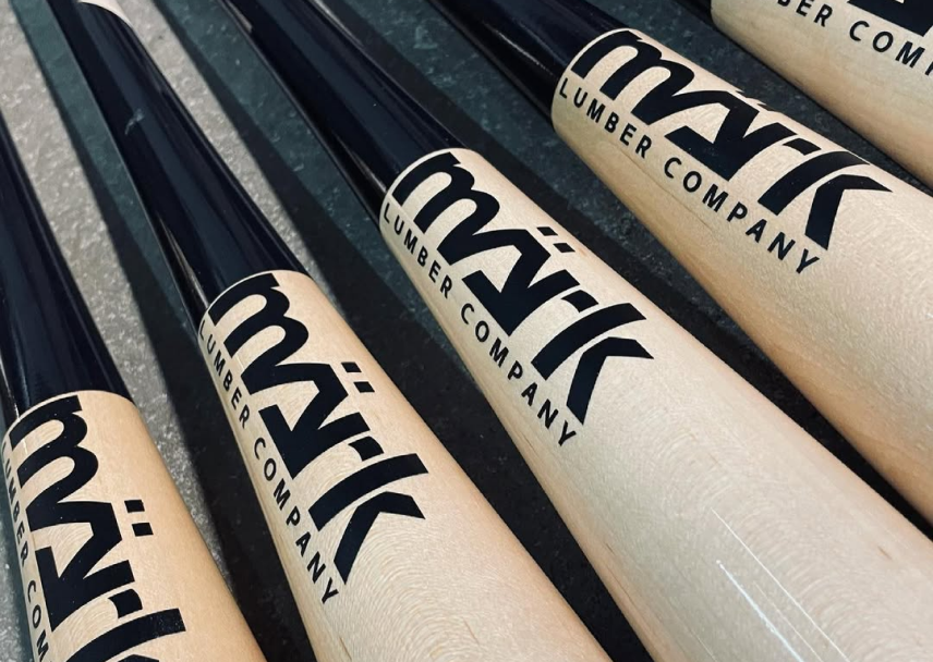 Mark Lumber Company wood baseball bats with black handles and natural barrels lined up on a surface.